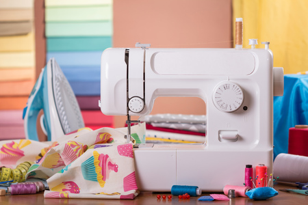 Sewing machine in work and accessories, on background of fabric samplesの写真素材
