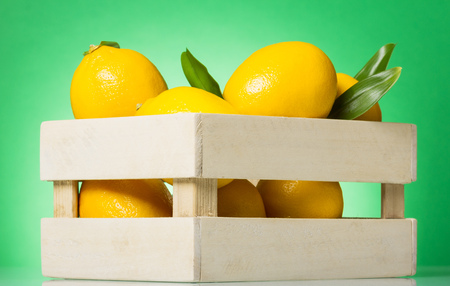 Wooden box with lemons on green backgroundの写真素材