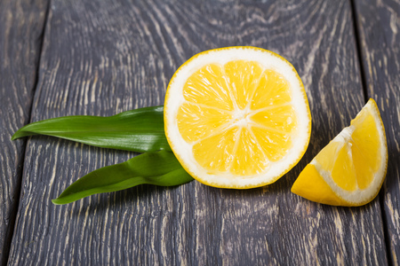 Lemon pieces with green leaves on wooden surfaceの写真素材