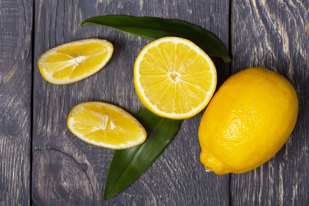 Large yellow lemon, citrus pieces, against wooden surfaceの写真素材