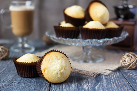 Slide of cupcakes in glass stand, near cupcakes in molds, on gray tableの写真素材