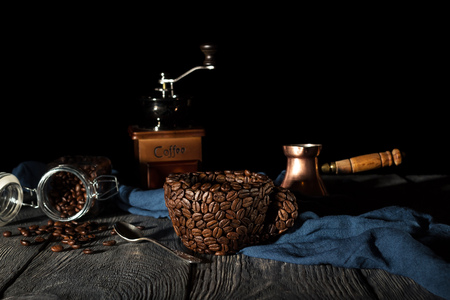 Improvised Cup made from coffee beans, hand mill on blue fabric, isolated on blackの写真素材