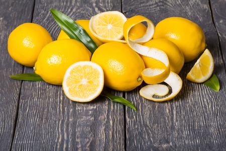 Bright yellow lemons and peeled zest, on grey surfaceの写真素材