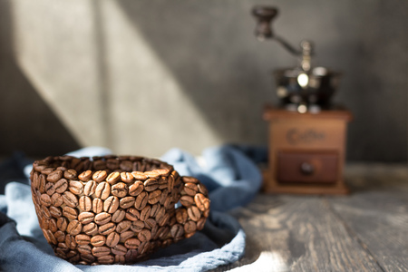 Cup made of coffee beans and hand mill, on fabricの写真素材