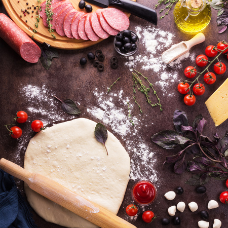 Layer of dough and ingredients for pizza, on dark working surfaceの写真素材