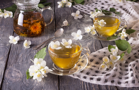 Steam over Cup of hot tea with Jasmine, flowers are scattered on gray surfaceの写真素材