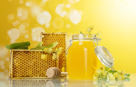 Bee wooden frame, jar with honey and spindle on yellow backgroundの写真素材