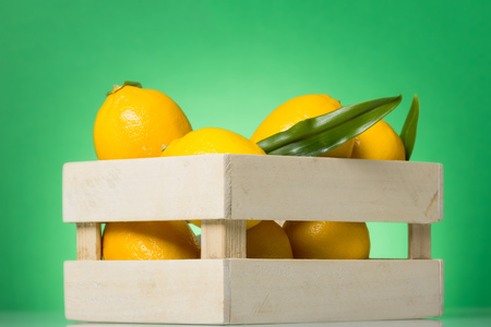 Full box of large yellow lemons close-up, on green backgroundの写真素材