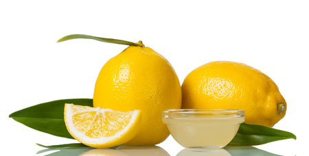 Two large lemons with leaves, lemon juice in small bowl isolated on whiteの写真素材