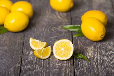 Slices of lemon lies on wooden surface, far away large yellow lemonsの写真素材