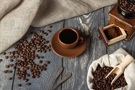 Coffee beans, ground coffee and hot drink in a Cup, on wooden surfaceの写真素材