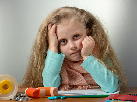 Patient child sitting at table, next to inhaler and pillsの写真素材