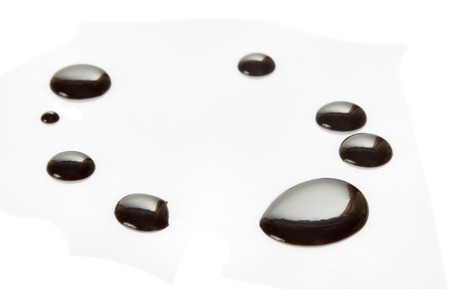 Shiny drops of black melted chocolate isolated on whiteの写真素材