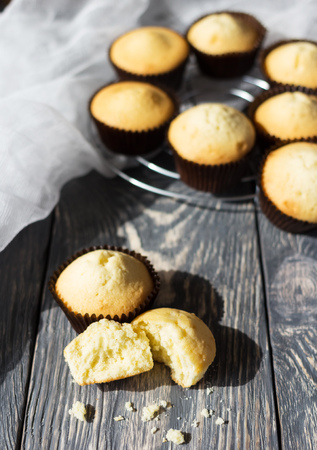 Many cupcakes in molds, one broken, on wooden surfaceの写真素材