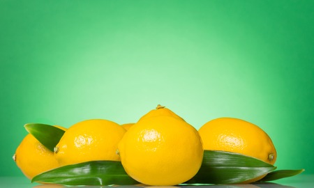 Large bright yellow lemons with leaves on greenの写真素材