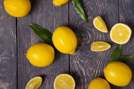Large yellow lemons and pieces are scattered on wooden surfaceの写真素材