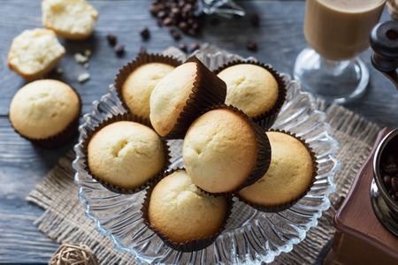 Freshly baked cupcakes in glass dish, Cup of cappuccino and manual coffee grinderの写真素材