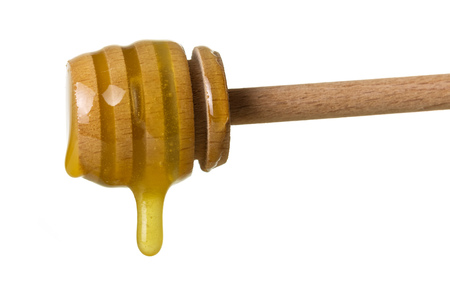 Goldish stream of honey dripping from wooden stirrer isolated on whiteの写真素材
