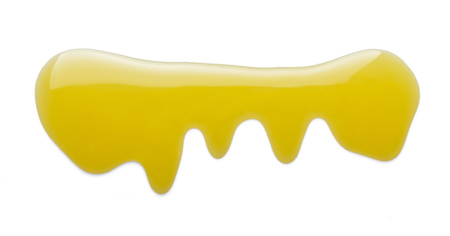 Small puddle of liquid goldish honey is isolated on whiteの写真素材