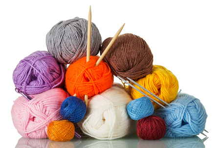 Skeins of yarn of different colors, shapes, quality, and two pairs of knitting needles isolated on whiteの写真素材