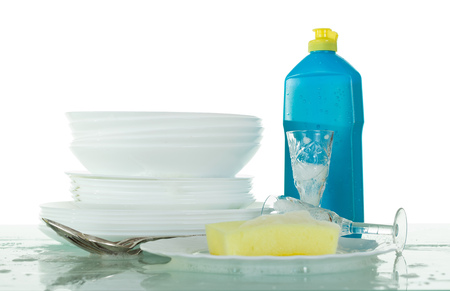 Clean crockery in soapy foam, bottle with detergent and sponge isolated on whiteの写真素材