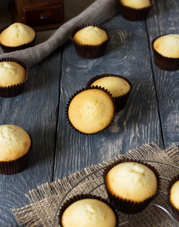 Lots of delicious cupcakes in molds on wooden surfaceの写真素材