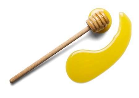 Wooden spoon stirrer and spread puddle of honey, isolated on whiteの写真素材
