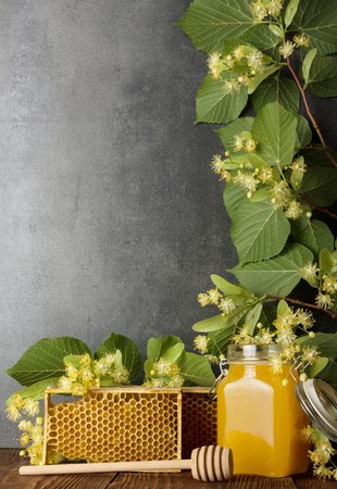 Branch of flowering Linden and jar of fresh honey on grayの写真素材
