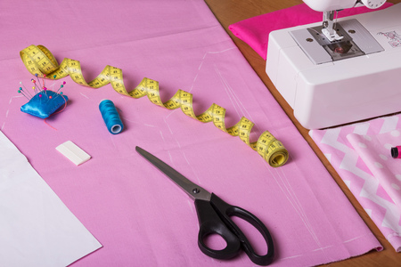 Sewing machine, centimeter, chalk and scissors on pink fabricの写真素材