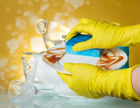 Womens hands in gloves wash dirty dishes with detergent on yellowの写真素材