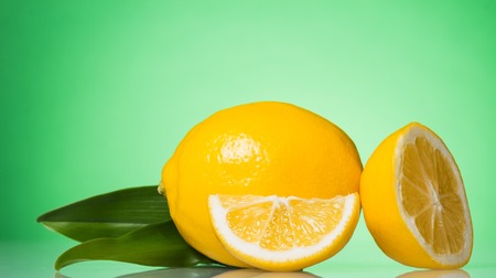 Juicy yellow lemon and slices, on green backgroundの写真素材