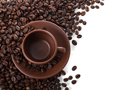 Ceramic Cup and saucer stands on scattered coffee beans isolated on whiteの写真素材