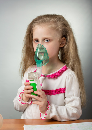 Little sick girl breathing using nebulizer, on grayの写真素材