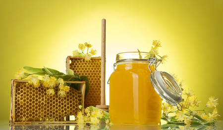 Wooden frames with wax honeycomb and honey in jar, on yellow backgroundの写真素材