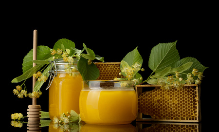 Jars with honey, spoon and honeycomb, isolated on blackの写真素材