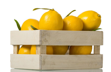 Lots of ripe yellow lemons in wooden box isolated on whiteの写真素材