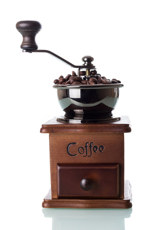 Hand coffee mill is full of grains isolated on whiteの写真素材