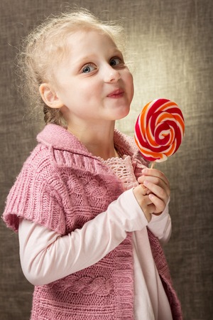Little smiling girl tastes the candyの写真素材