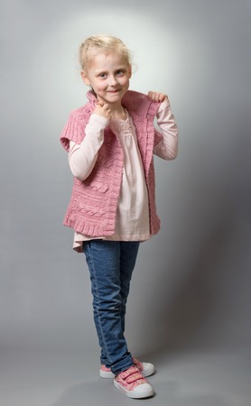 Charming blonde fashionista shows off her clothes, on grayの写真素材