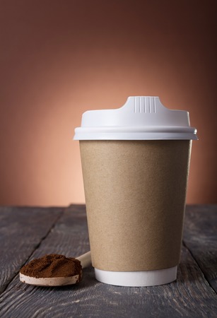 Special container for take-away coffee, ground coffee into spoon on tableの写真素材