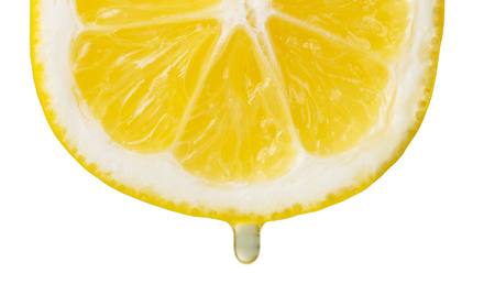 Cut slice of lemon with drop of juice isolated on whiteの写真素材