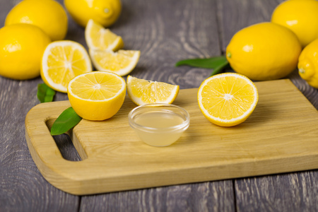 Lot of whole lemons and pieces, bowl of lemon juice on cutting Boardの写真素材