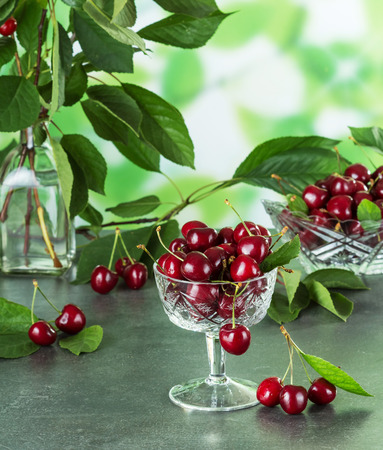 Crystal vases with ripe cherries, near on surface three berriesの写真素材