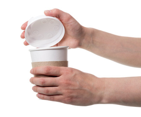 Womens hands open lid of Cup of coffee, isolated on whiteの写真素材