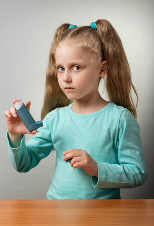 Sick child with an inhaler, on gray backgroundの写真素材