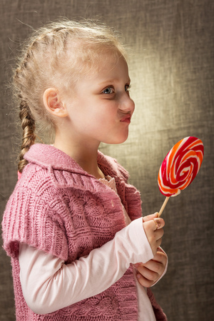 Curly blonde girl doesnt like candy on stickの写真素材