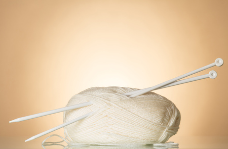 White wool skein of yarn and knitting needles on light beige backgroundの写真素材