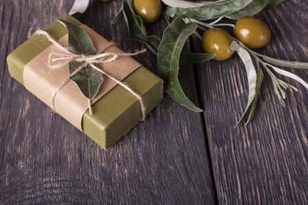 Olive handmade soap with a fresh branch on a wooden backgroundの写真素材