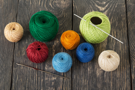 Multi-colored woolen balls and crochet hooks on dark wooden boardsの写真素材