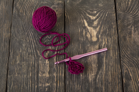 Purple wool thread for knitting and a pink hook on beautiful dark boardsの写真素材